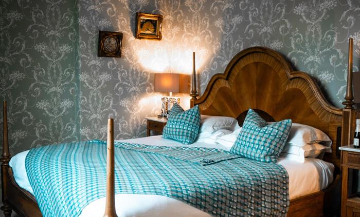 A large, luxurious room with a triple aspect overlooking beautiful open countryside. The centerpiece is a king-size bed. And the indulgence continues
